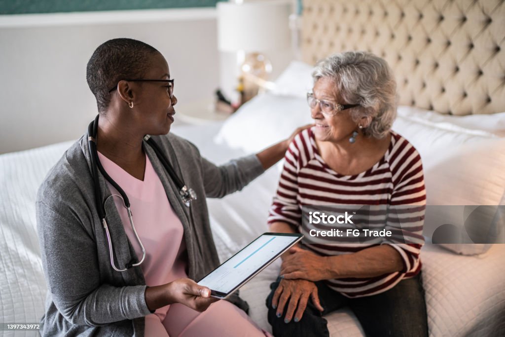 Doctor talking to a senior woman in the bedroom Nurse Stock Photo