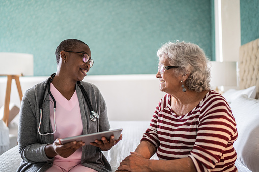 Doctor talking to a senior woman in the bedroom