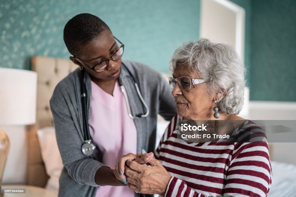 Home caregiver helping a senior woman standing in the bedroom Alzheimer's Disease Stock Photo