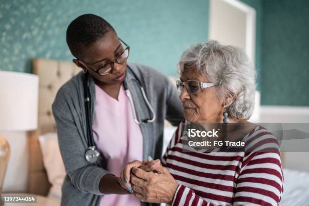 Home Caregiver Helping A Senior Woman Standing In The Bedroom Stock Photo - Download Image Now