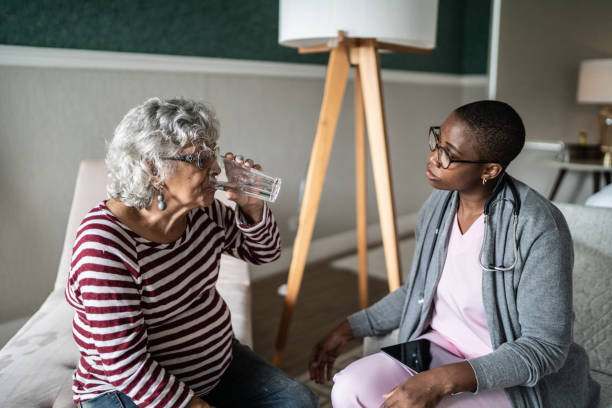 istock Senior woman drinking water with a nurse's help in the bedroom 1397344207