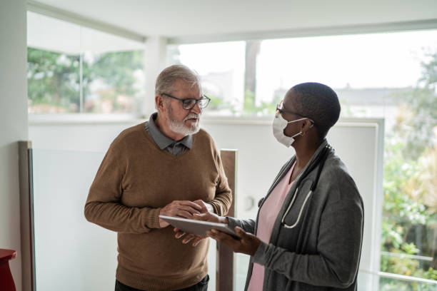 istock Nurse talking to patient at home - using face mask 1397344937