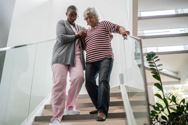 Nurse helping a senior woman walking the stairs Nurse helping a senior woman walking the stairs walking aide stock pictures, royalty-free photos & images