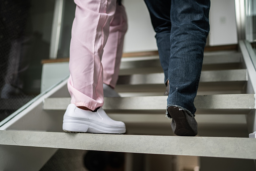 Low section of a nurse helping a senior woman walking the stairs