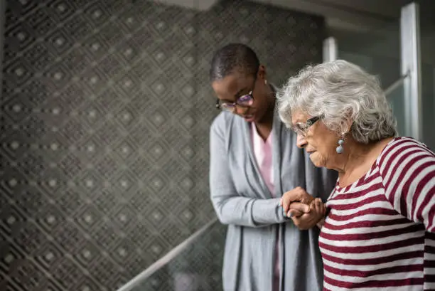 Photo of Nurse helping a senior woman walking the stairs