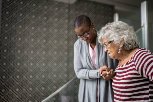 nurse helping a senior woman walking the stairs - senior adult home caregiver care community outreach imagens e fotografias de stock