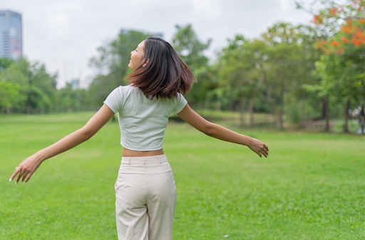 Photograph of a young asian lady chilling and relaxing in a park by doing different activities.