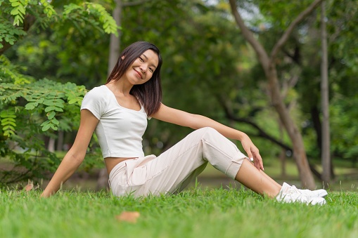 Photograph of a young asian lady chilling and relaxing in a park by doing different activities.
