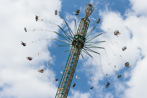 Low angle view teenage friends enjoying a funfair in Newcastle, North East of England. They are on a swing ride laughing and having fun.