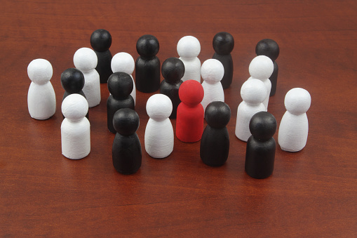 Red colored figure in crowd of black and white people figures. Talent concept.