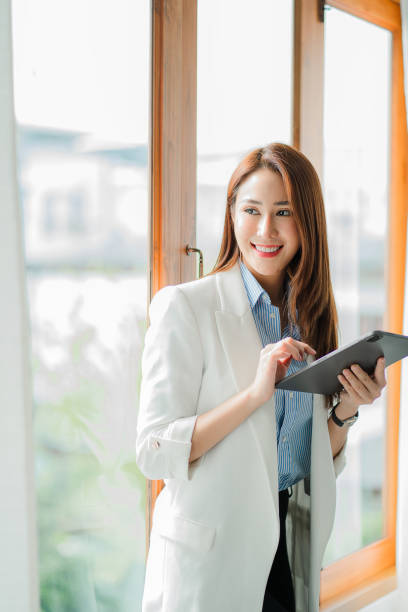 istock A cheerful, confident, professional, beautiful young Asian businesswoman using a digital tablet stands in an office building representing an online business idea. 1397353653