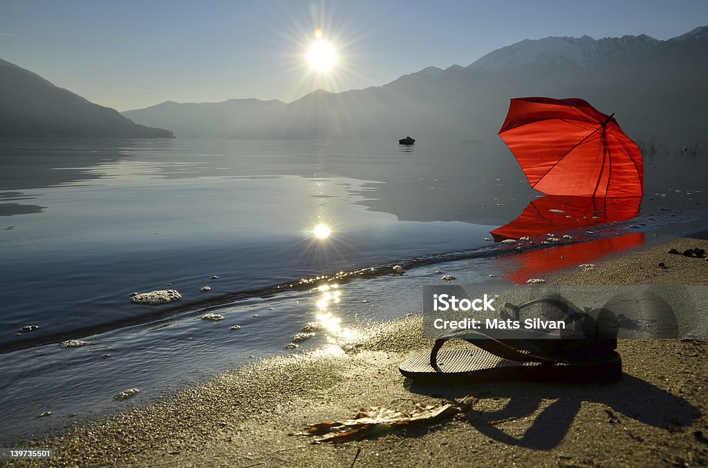Infradito e un ombrellone sulla spiaggia rosso - Foto stock royalty-free di Lago