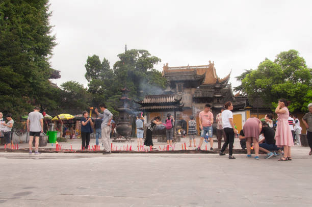 des touristes chinois brûlent de l’encens dans un temple bouddhiste - zhenjiang photos et images de collection