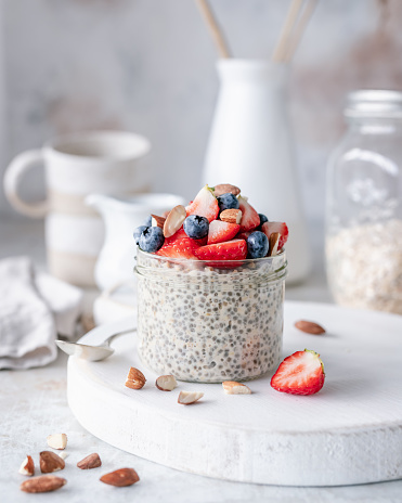 Breakfast scene with a jar of overnight chia oats topped with strawberries, blueberries and chopped almonds