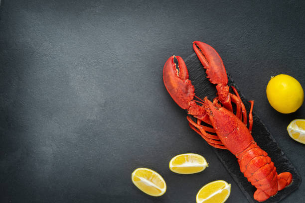 istock Red lobster with lemon on dark background. Directly above, copy space. 1397357367