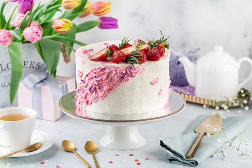 An elegant dessert table for a party or wedding featuring ornate cakes, macaroon tree, tarts wedding favors and rose petals.