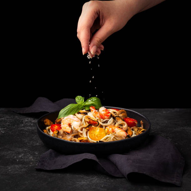 Pasta seafood. Pasta Spaghetti with shrimp, cream sauce and basil, sprinkle with cheese Top view on black wooden table.