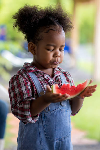 dziecko jedzące świeżego arbuza. dziecko mała dziewczynka trzymająca arbuza. urocza młoda dziewczynka jedząca arbuza - juicy childhood colors red zdjęcia i obrazy z banku zdjęć