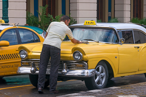 Havana, Cuba - January 15, 2016: Taxi driver cleaning his car in the historic center of the city
