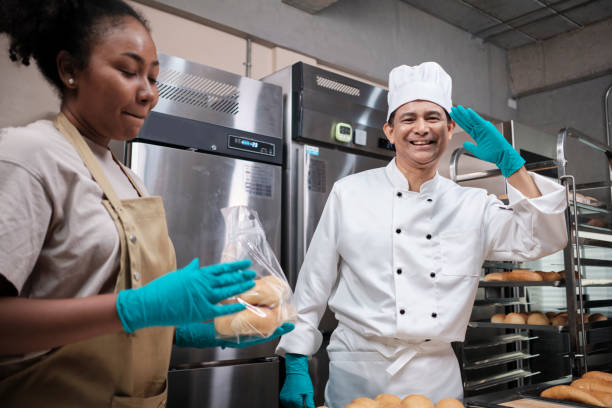 istock Two professional chefs in uniforms look at camera, cheerful with bread products. 1397369029