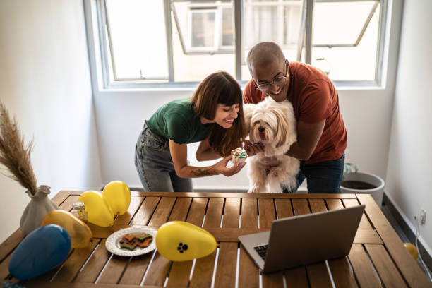 istock Couple celebrating dog's birthday doing a virtual party using laptop at home 1397371130
