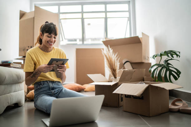 jeune femme regardant un cadre photo dans une nouvelle maison - affaires personnelles photos et images de collection