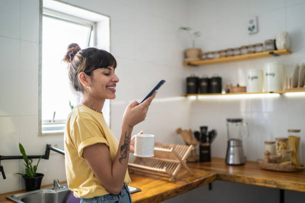 istock Young woman using the mobile phone while drinking coffee or tea at home 1397371576