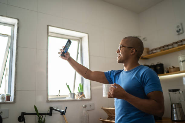 Young man filming or taking a selfie using mobile phone at home