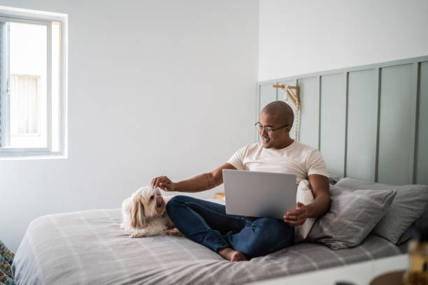 istock Young man taking care of his dog while using the laptop at home 1397371656