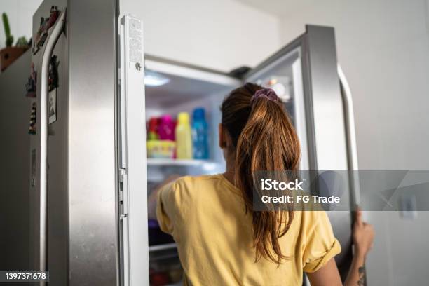 Rear View Of A Young Woman With Refrigerator Door Open Stock Photo - Download Image Now