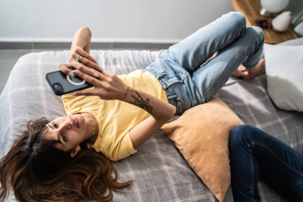 istock Young woman using the mobile phone in the bed at home 1397372189