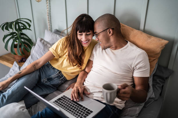 istock Young couple using the laptop in the bed at home 1397372250