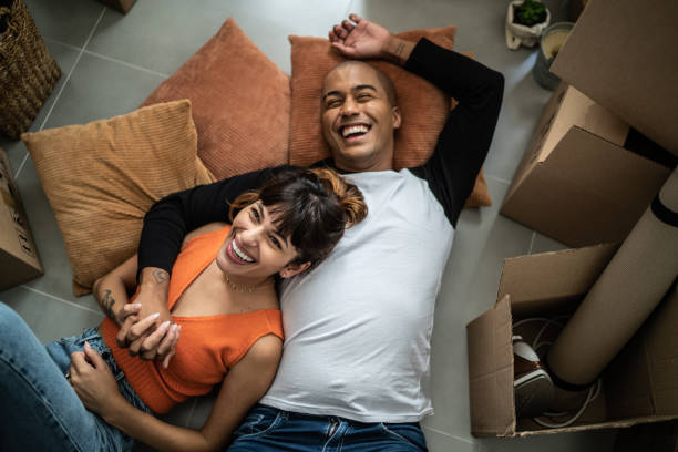 新しい家で床に横たわって幸せな若いカップル - mover ストックフォトと画像