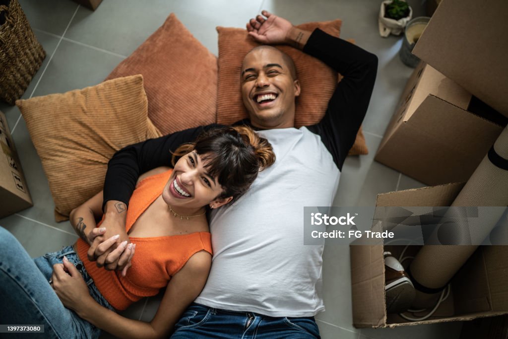 Happy young couple lying on the floor at new home Couple - Relationship Stock Photo