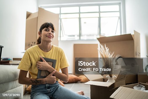istock Young woman change home and holding frame photo contemplating 1397373090