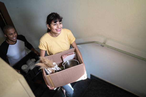 istock Happy couple carrying boxes and moving up stairs 1397373370