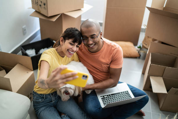 istock Young couple taking a selfie or filming using mobile phone while packing moving boxes at home 1397373441
