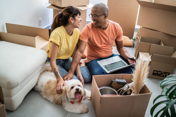 young couple packing and moving boxes at home - moving house apartment couple box imagens e fotografias de stock