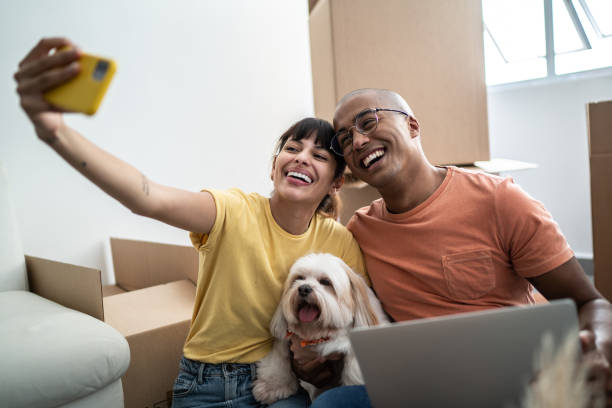 istock Young couple taking a selfie or filming using mobile phone while packing moving boxes at home 1397373479