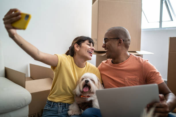 istock Young couple taking a selfie or filming using mobile phone while packing moving boxes at home 1397373499