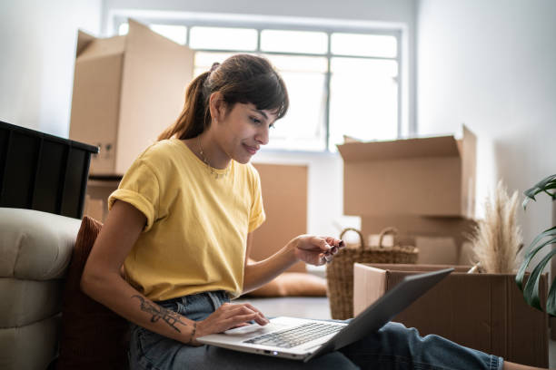 istock Young woman doing online shopping using laptop at new home 1397373561