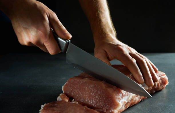 istock The chef is cutting fresh raw meat into steaks. Close-up on a gray background. 1397373594