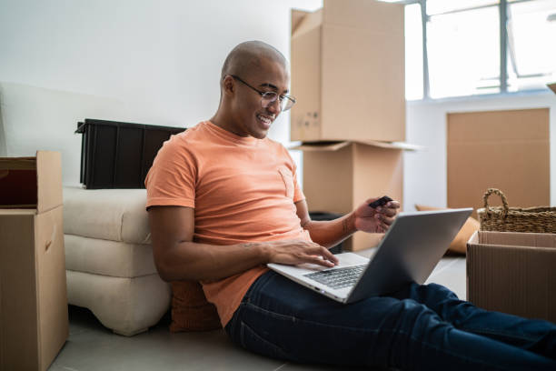 istock Young man doing online shopping using laptop at new home 1397373595