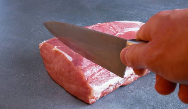 istock The chef is cutting fresh raw meat into steaks. Close-up on a gray background. 1397373597