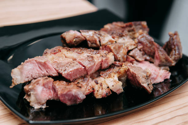 kochen von ribeye-steaks und fleischbrötchen im kochkurs. geschnittenes fleisch auf einem teller, nahaufnahme. - animal bone chop close up color image stock-fotos und bilder