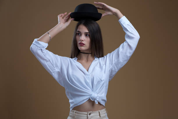 istock A girl in a white blouse with a black hat on a beige background 1397376176