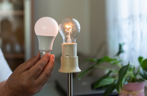 Power saving concept.Man changing compact-fluorescent (CFL) bulb with new LED light bulb.