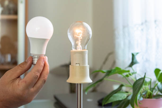 istock Power saving concept.Man changing compact-fluorescent (CFL) bulb with new LED light bulb. 1397383277