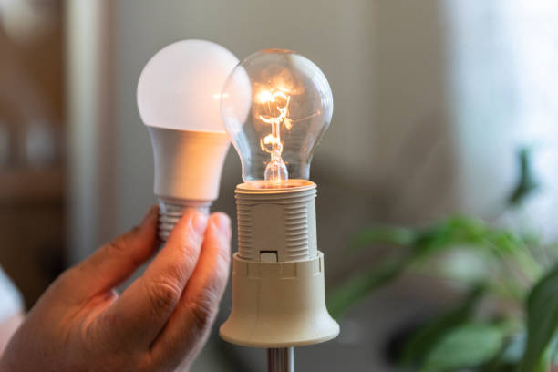 istock Power saving concept.Man changing compact-fluorescent (CFL) bulb with new LED light bulb. 1397383279