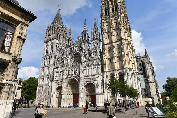 Rouen, France-05 04 2022: People passing in front of the Rouen Cathedral. The Rouen Cathedral is a Roman Catholic church in Rouen, Normandy, France.It is famous for its three towers, each in a different style.It also has a place in art history as the subject of a series of impressionist paintings by Claude Monet.